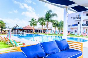 une vue sur la piscine du complexe avec un canapé et des chaises dans l'établissement Yiannis Manos Hotel Resort, à Mália
