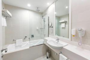 a white bathroom with a sink and a bath tub at Citymax Hotel Ras Al Khaimah in Ras al Khaimah