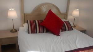 Una cama con dos almohadas rojas encima. en Jessamine House Hotel en Gravesend