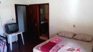 Pousada Arco Íris في Tabapira: غرفة نوم صغيرة بها سرير وتلفزيون