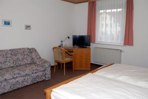 a bedroom with a bed and a couch and a tv at Landhotel Lützen-Stadt in Lützen