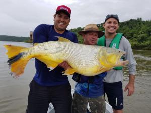 two men holding a large fish in the water at Sentirse en casa in Puerto Iguazú