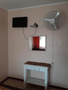 Habitación con mesa, ventilador y espejo. en Hotel La Palmera en Villa Gesell