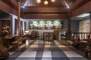a lobby of a restaurant with a large painting on the wall at Ayuterra Resort in Ubud