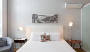 a bedroom with a large white bed and a chair at Trindade Premium Suites & Apartments in Porto