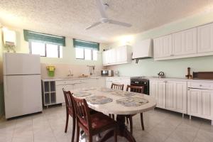 a kitchen with white cabinets and a table with chairs at Satori Gozo Centre - Apartment Bufo in Xagħra