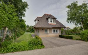 a small house with a thatched roof on a driveway at Resort Citta Romana in Hellevoetsluis