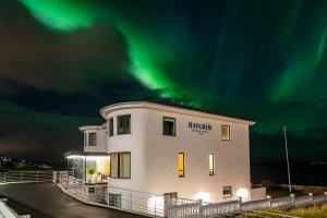 a building with the northern lights in the sky at Havgrim Seaside Hotel 1948 in Tórshavn