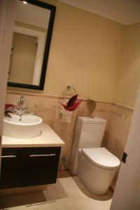 
a bathroom with a toilet, sink, and mirror at The Atrium Resort in Grace Bay
