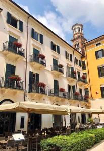 a building with tables and umbrellas in front of it at Residenza Navona Verona in Verona