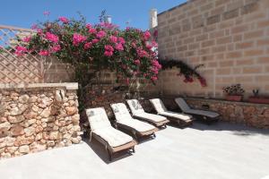 a group of chairs and flowers on a wall at Gozo Holiday Apartmen - 2 Bedroom Villa with Shared Pool in Xagħra