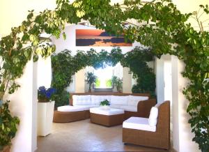 a living room with white couches and plants at Hotel Villa Smeraldo in Orbetello