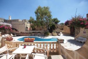 a patio with a pool and tables and chairs at Gozo Holiday Apartmen - 2 Bedroom Villa with Shared Pool in Xagħra +13 photos