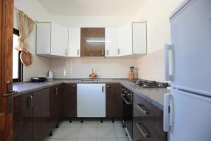 a kitchen with wooden cabinets and a white refrigerator at Gozo Holiday Apartmen - 2 Bedroom Villa with Shared Pool in Xagħra