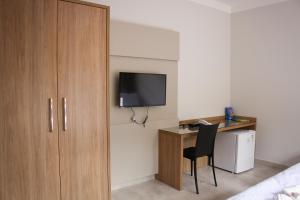 Habitación con escritorio, TV y cama. en Pousada Primaz de Minas en Mariana