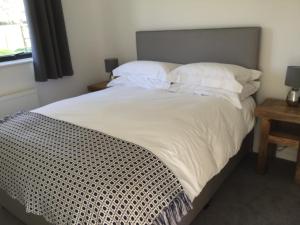 a bed with white sheets and pillows in a bedroom at The Old Flower Field in Hurstpierpoint