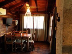 comedor con mesa y sillas y ventilador de techo en X Sierras Cabañas en Villa Carlos Paz