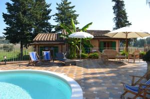 a pool with chairs and umbrellas next to a house at Agriturismo Rosa dei Venti in Pomarance