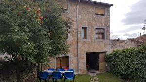 una mesa con sillas azules frente a un edificio en Casa Rural el Casillo del Abuelo Goyo, en Navarredonda de Gredos