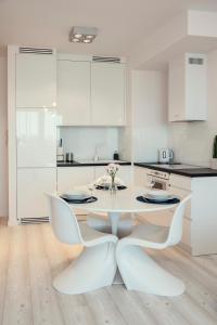 een witte keuken met een witte tafel en stoelen bij Unique 3city Apartments - Ufo Apartment in Gdańsk