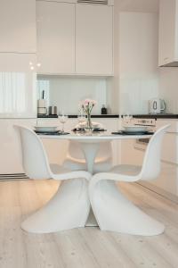 een witte keuken met een witte tafel en stoelen bij Unique 3city Apartments - Ufo Apartment in Gdańsk