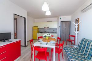 a kitchen and dining room with a table and red chairs at Columbus in Bibione