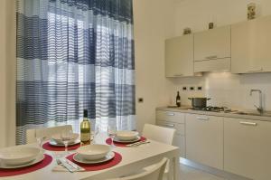 a white kitchen with a table with wine glasses at Tolomeo Rooms in Paestum