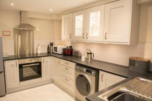 a kitchen with white cabinets and a washer at 138a Old Star & Garter in Ludlow
