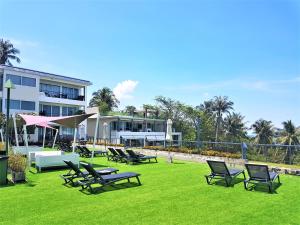 a group of chairs sitting on the grass in front of a building at KB Apartments Karon Beach by PHR in Karon Beach