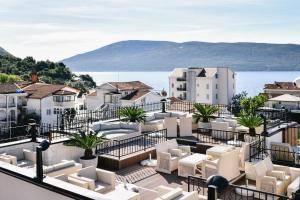 einen Balkon mit weißen Stühlen und Blick auf das Wasser in der Unterkunft Wellness & Spa Hotel ACD in Herceg-Novi