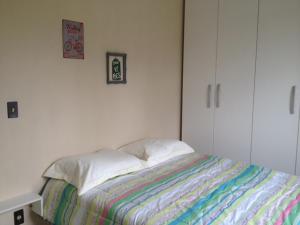 a white bedroom with a bed with a colorful blanket at Apartamento Vila do Sol in Blumenau