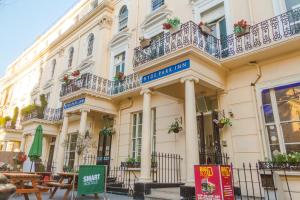 a building with a balcony and tables in front of it at Smart Hyde Park Inn in London