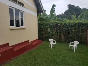 two chairs sitting in the grass next to a house at Family Friendly Stay near Entebbe Airport in Entebbe