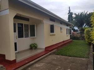 a house with a green yard in front of it at Family Friendly Stay near Entebbe Airport in Entebbe