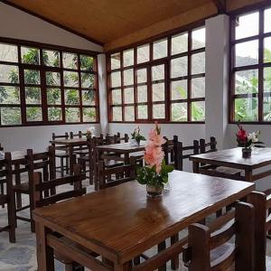 a dining room with tables and chairs and windows at Eco Hacienda Roman in Machu Picchu