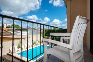 balcone con sedia bianca e piscina di Hotel Roble Blanco a Chascomús