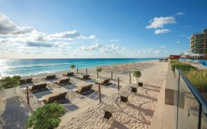 uma praia arenosa com espreguiçadeiras e o oceano em Hard Rock Hotel Cancun - All Inclusive em Cancún