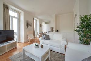 ein weißes Wohnzimmer mit einem weißen Sofa und einem TV in der Unterkunft Príncipe Charming in Lissabon