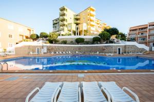 a swimming pool with lounge chairs in front of a building at Orlando 85 in Adeje