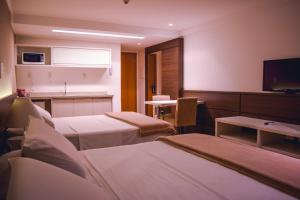 a hotel room with two beds and a kitchen at Hotel Atmosfera Feira de Santana in Feira de Santana