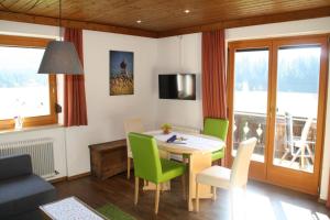 un soggiorno con tavolo da pranzo e sedie verdi di Wirtseppelerhof Apartments a Leutasch