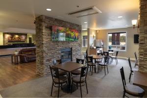a restaurant with tables and chairs and a fireplace at Kanata Whitecourt in Whitecourt