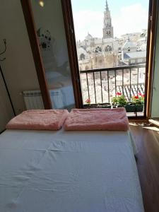 a bed in a room with a view of a city at Apartamento PRANA Junto al Alcázar in Toledo