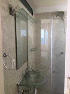 y baño con lavabo de cristal y ducha. en Apartamento frente ao mar, en Balneário Camboriú