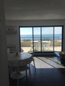 een woonkamer met een tafel en uitzicht op de oceaan bij Exceptionnel, sur la plage en front de mer in Le Grau-du-Roi