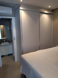 a bedroom with a white bed and a bathroom at Estacofor Santos - Apto 1105 in Santos