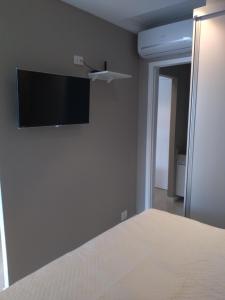 a bedroom with a bed and a flat screen tv on the wall at Estacofor Santos - Apto 1105 in Santos
