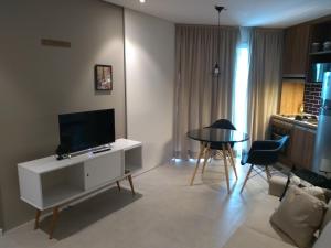 a living room with a television and a table and chairs at Unique Santos - Flat 1105 in Santos