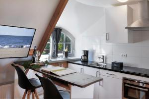 a kitchen with a table with chairs and a tv at Villa Mare in Sint Maartensbrug