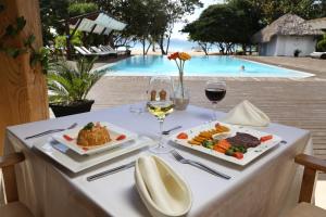 a table with food and wine and a swimming pool at Punta Rucia Lodge Hotel Boutique & Spa in Punta Rucia